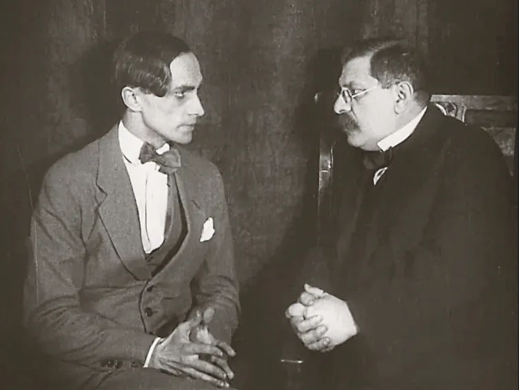 a black and white film still of two men in suits
