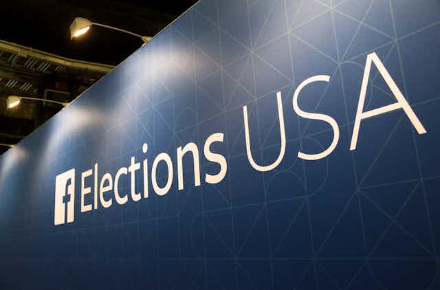 an exterior wall topped by streetlights and bearing writing that says "Elections USA" next to a Facebook logo.