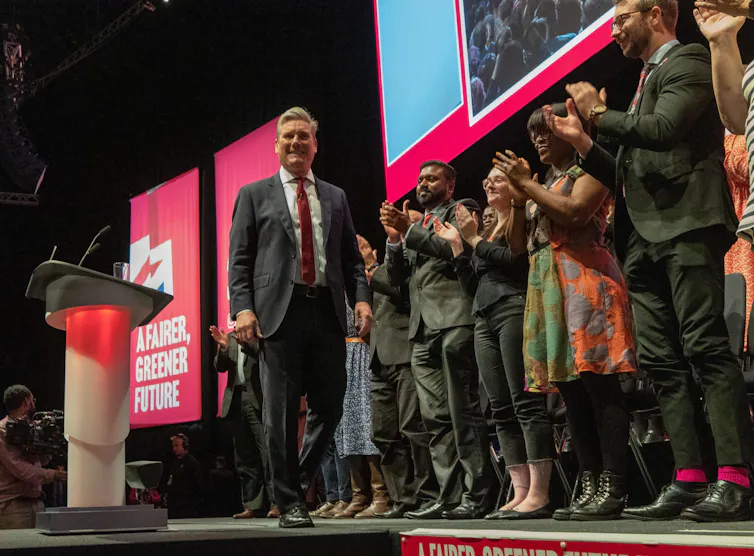 Keir Starmer on stage in front of a row of people clapping.