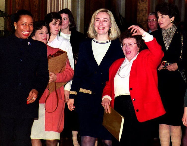 Female legislators smile and pose with First Lady Hillary Rodham Clinton.
