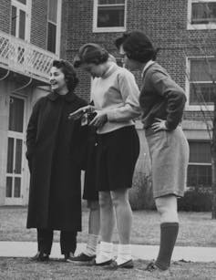Black and white photo of four young women, three of whom are wearing shorts.