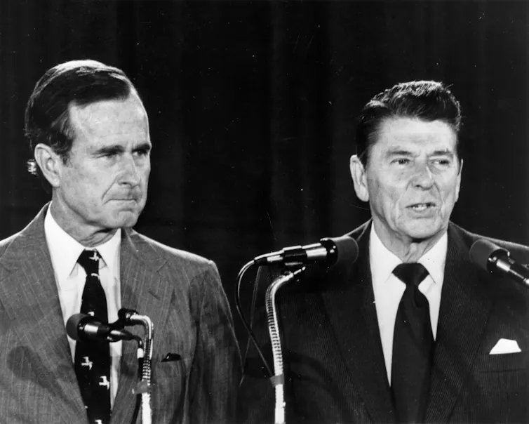 Two men in suits and ties in front of microphones.