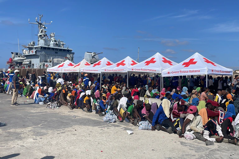Numerosos migrantes bajo toldos de la Cruz Roja en el puerto de Lampedusa.