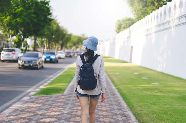 A woman walks in a suburb with a backpack on her back.