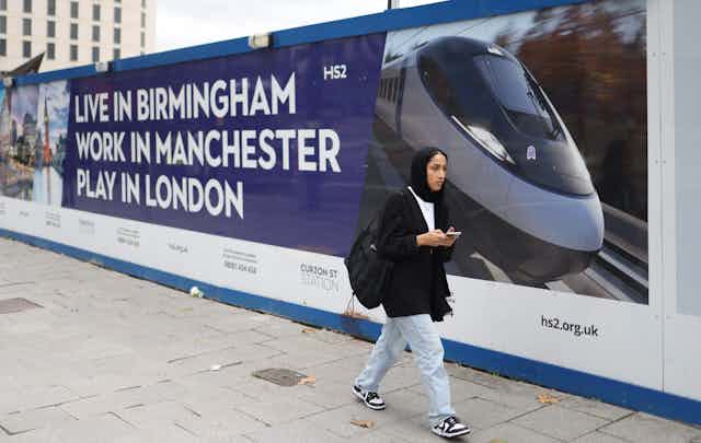 A woman walks past advertising hoarding for the HS2 High speed rail link by the Curzon Street station in Birmingham.