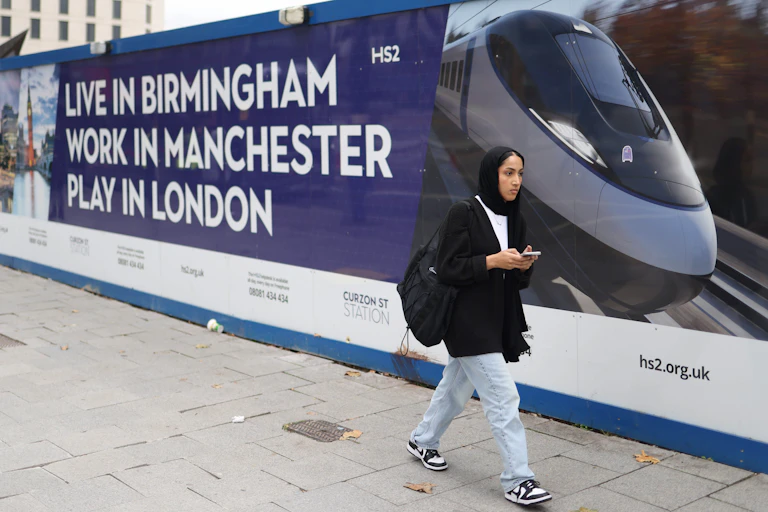 A woman walks past advertising hoarding for the HS2 High speed rail link by the Curzon Street station in Birmingham.