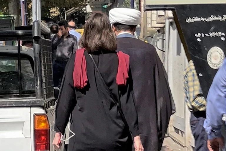 Femme de dos, cheveux non couverts, dans une rue