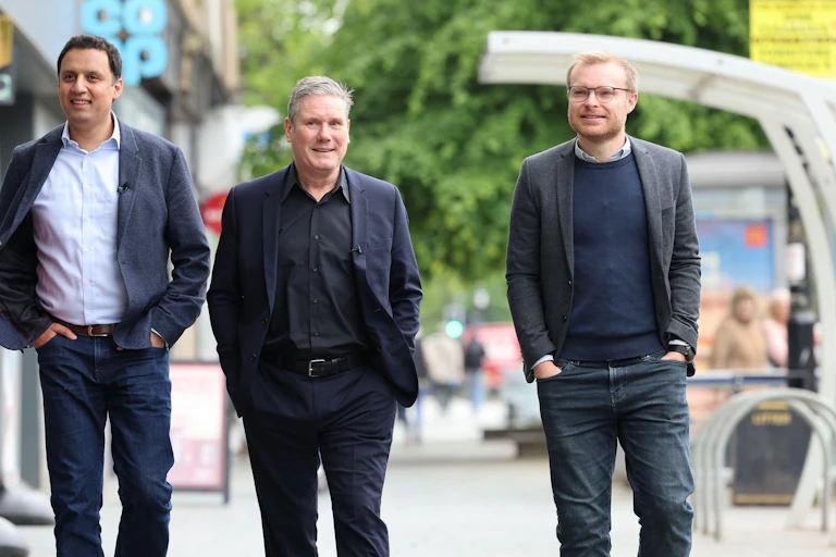 Anas Sawa, Keir Starmer and Michael Shanks walking down a high street.