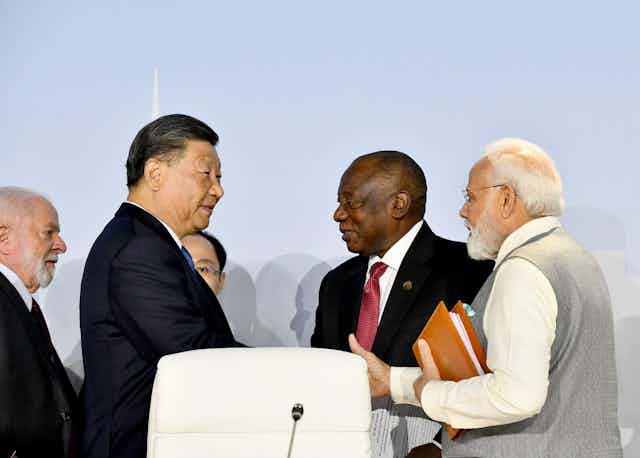 China's leader Xi Jinping at the 2023 Brics meeting, shaking hands with other leaders.