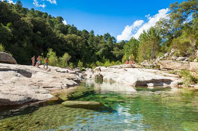 Photo de baigneurs au bord de piscines naturelles, en Corse.