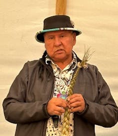 A man seen holding a braid of sweetgrass.