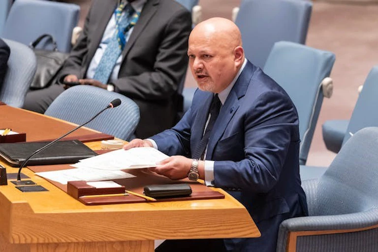 Un homme tient des documents et parle dans un microphone