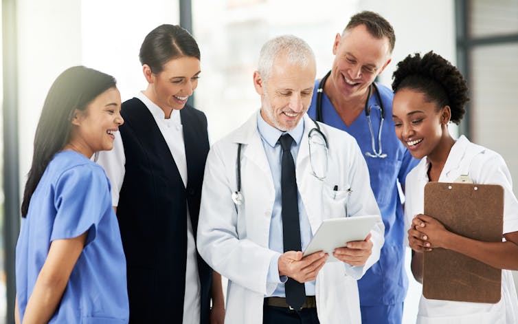 A group of health professionals, some wearing scrubs and white coats