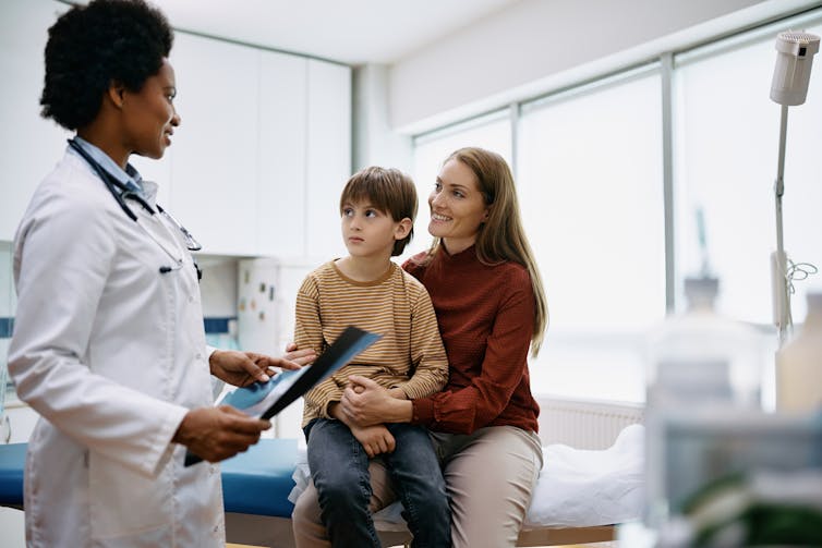 A doctor in an examining room with a woman and child