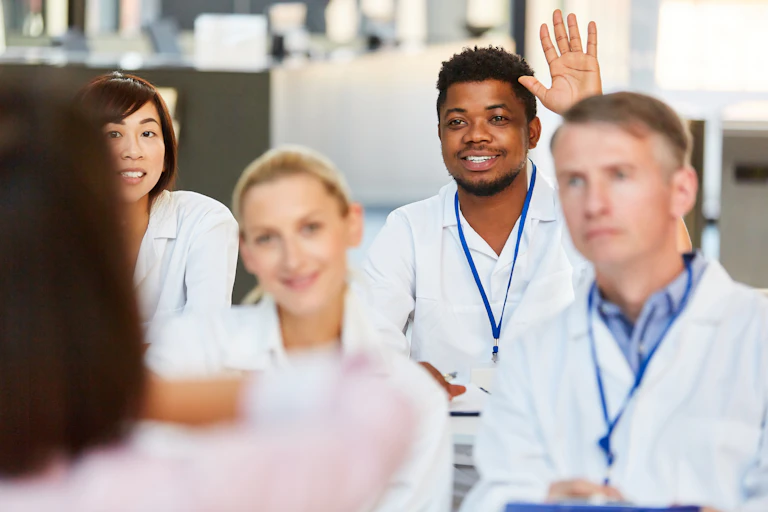 A group of medical students, one with his hand raised