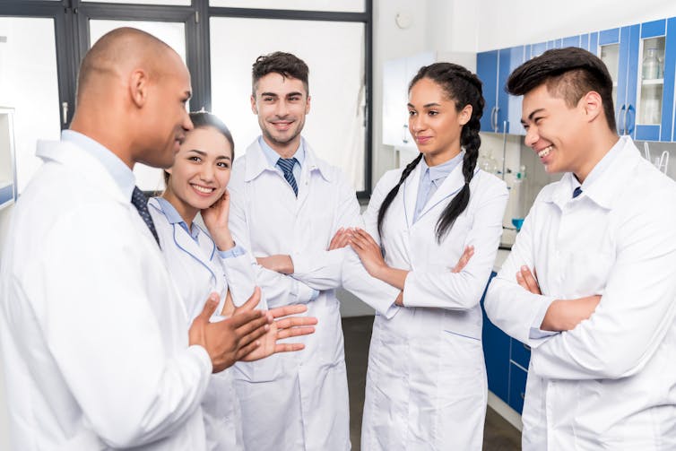A group of people in white coats listening to a colleague