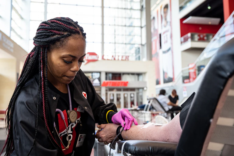 A phlebotomist tends to a blood donor at a blood drive.