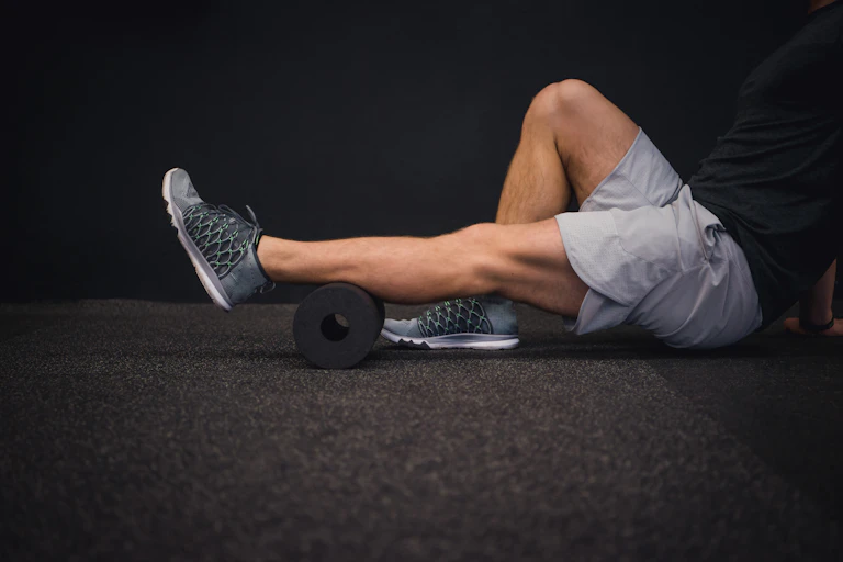 A man uses a foam roller on his leg.