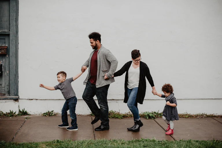 A man and woman lead two small children along a footpath.