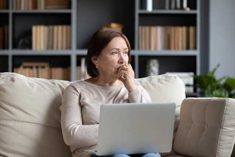 A women on a laptop with a pensive look on her face.