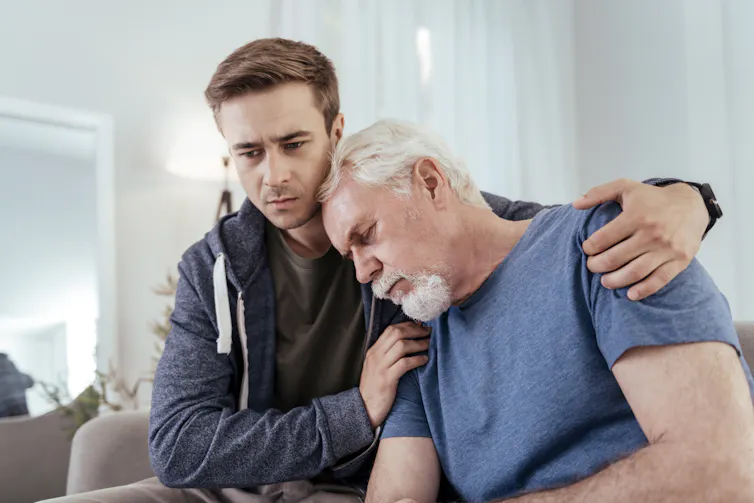 Um jovem com seus braços em volta de um homem mais velho