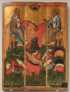 An icon painting with a gold background shows two men with crosses on their clothing sitting near about a dozen animals.