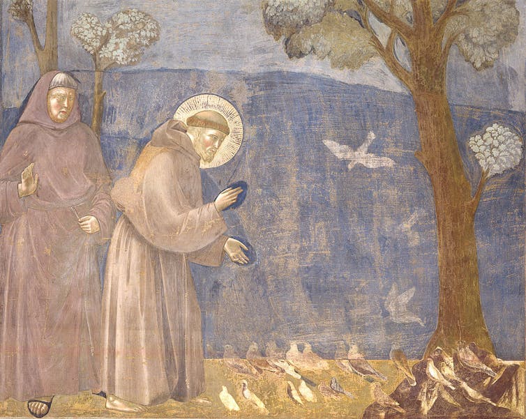 A religious icon painting in faded shades of blue and tan shows a man in monk's robes land a halo looking at birds on the ground.