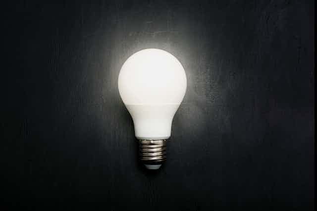 A photo of a glowing white LED light bulb on a black background.