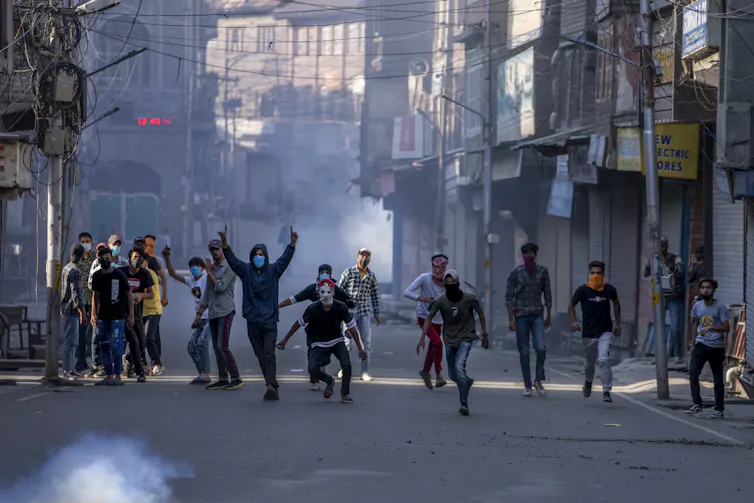 Young men fight and protest on a smoky street.