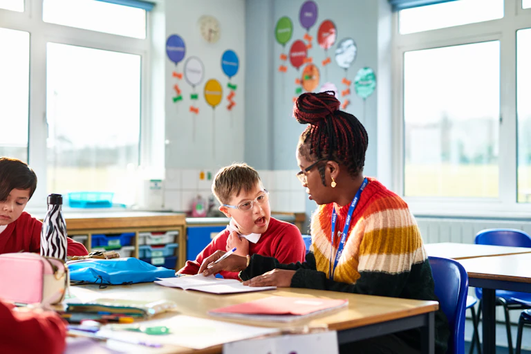 classroom setting, teacher helps child with disability