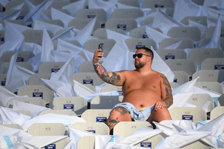 Un homme se prend en photo dans une tribune vide.