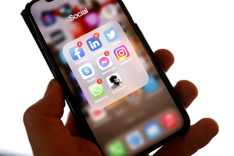 A hand holds a cellphone diplaying apps.