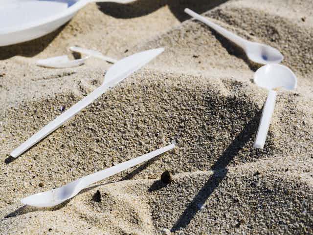 A close-up shot of plastic cutlery on sand at beach.