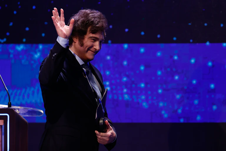 Javier Milei waving to audience as he steps down from podium