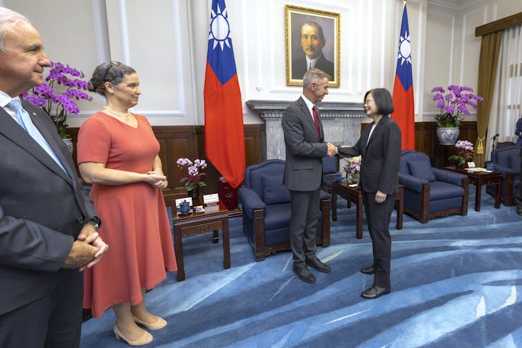 People stand in a row watching two people shake hands.