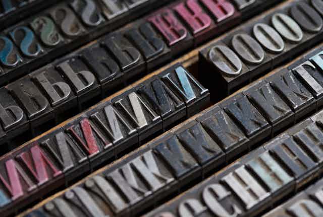 Vintage metal printing press letters are seen in close-up.