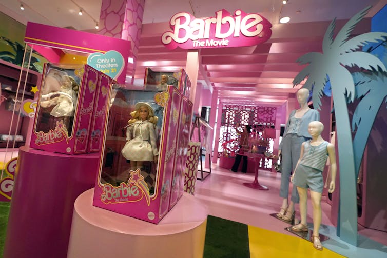 A corner of a department store with a 'Barbie' sign featuring mannequins in clothing and dolls