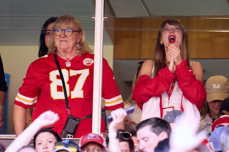 Taylor Swift and Donna Kelce both wear red in support of the Kansas City Chiefs as they watch the first half of an FNL game from a box seat.
