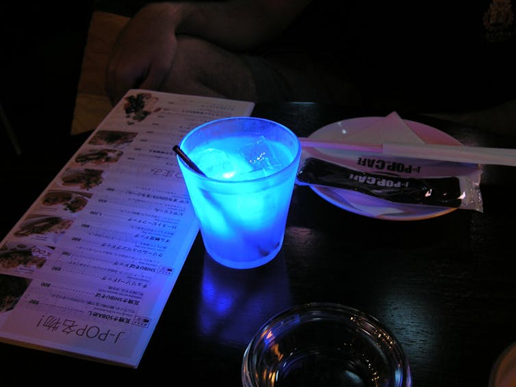 A glowing blue drink on a table in a dark restaurant