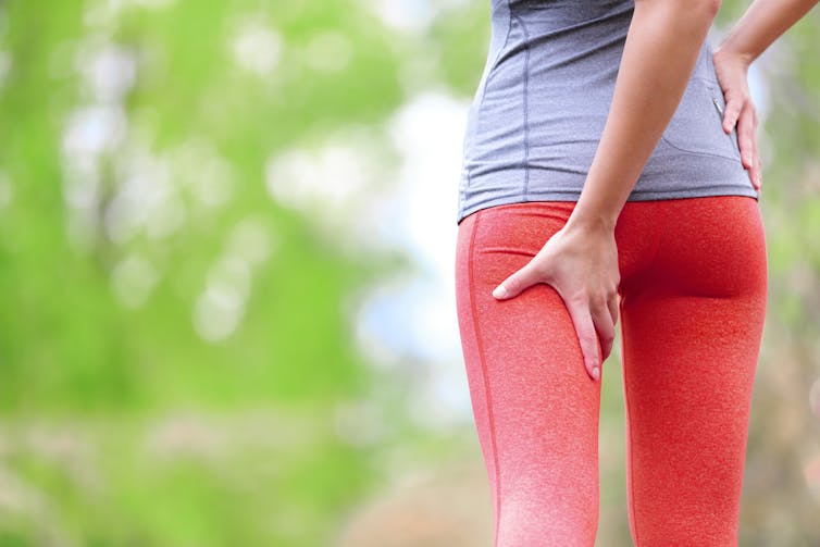 A woman clasps her lug in pain.