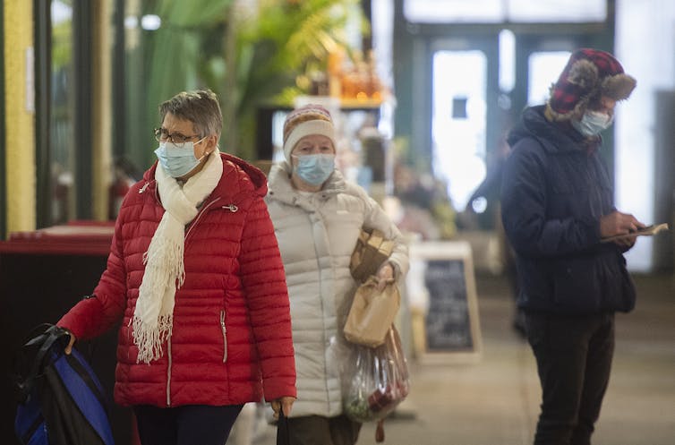 People in winter coats wearing face masks indoors