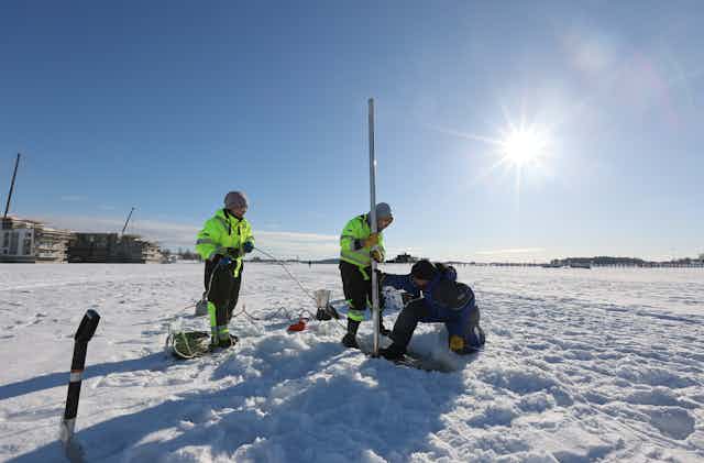 Four researchers on the ice of Lake Kallavesi in Finland.