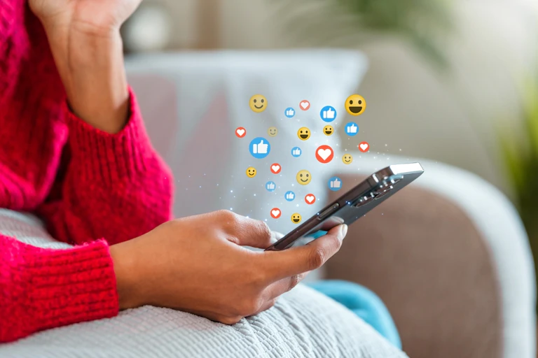 Une adolescente tenant un smartphone dans sa main et naviguant sur les réseaux sociaux