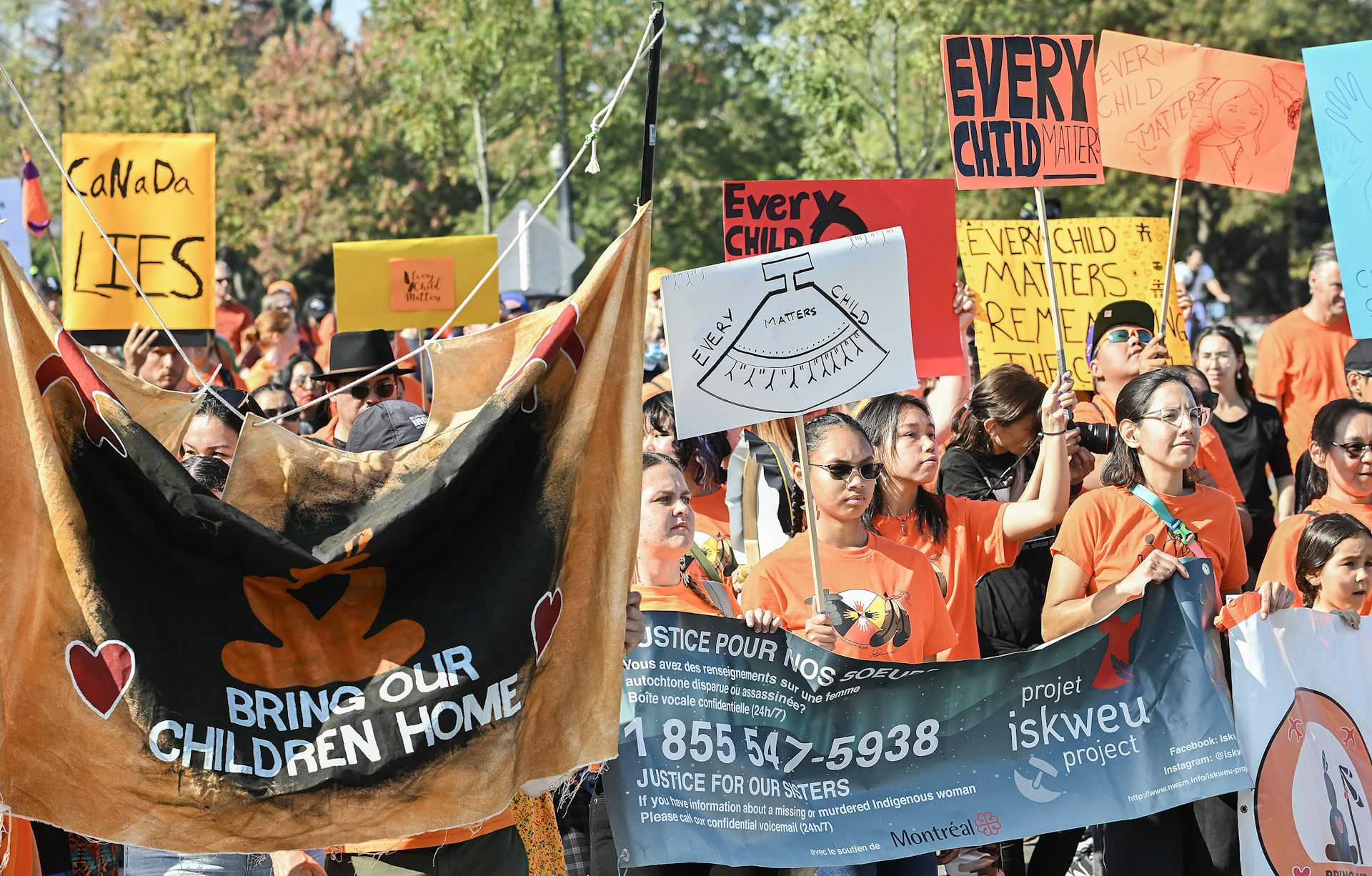 People seen at a rally carrying a banner that says 'bring our children home.'