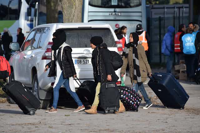 Des femmes migrantes se dirigent vers un bus, après le démantèlement du camp connu sous le nom de « Jungle » de Calais, en novembre 2016.