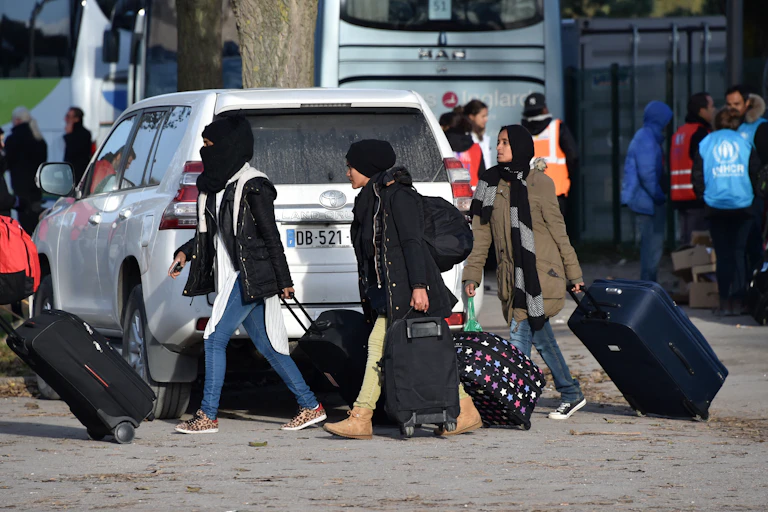 Des femmes migrantes se dirigent vers un bus, après le démantèlement du camp connu sous le nom de « Jungle » de Calais, en novembre 2016.