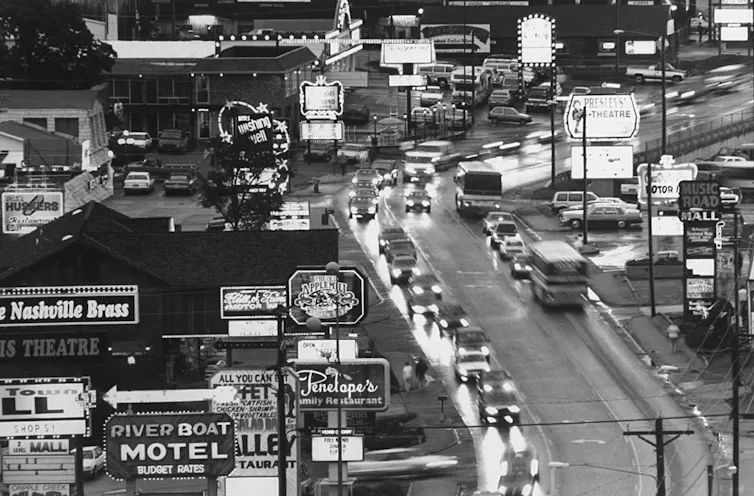 Bird's eye view of traffic winding through a main road replete with neon signs.