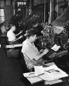 A black-and-white photo shows a row of Linotype machines -- large, intimidating-looking metal contraptions -- towering over the workers using them.