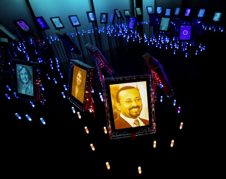 A picture of the 2019 Nobel Peace Prize laureate Ethiopian Prime Minister Abiy Ahmed Ali is on display at the Nobel Peace Center in Oslo, alongside other framed photos of people in a dark room with blue lighting.