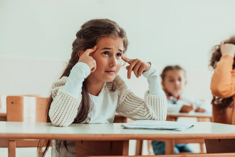 A child looking confused at a desk.